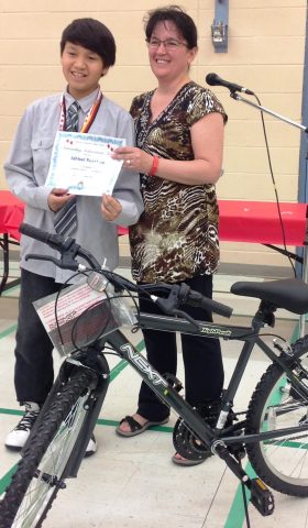  Pictured: Jahleel Roasting, Grade 6, receives his Outstanding Achievement Award, which includes a new bike, from Principal Gail Wilton. 