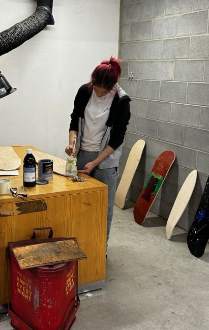 Grade 11 student Kascey Crier, designated Leader of the first semester carpentry class, works on her second skateboard project amid other student projects that she assisted with in December. (Photo credit: Jonathan Belinsky)